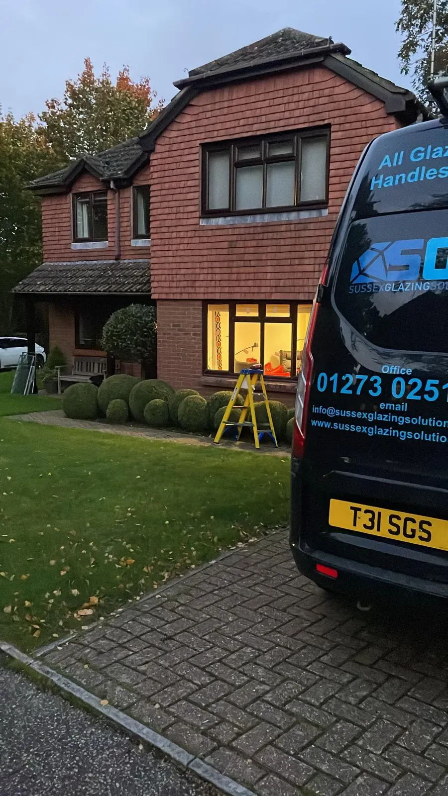 House with a van parked outside, neatly trimmed bushes, and a ladder