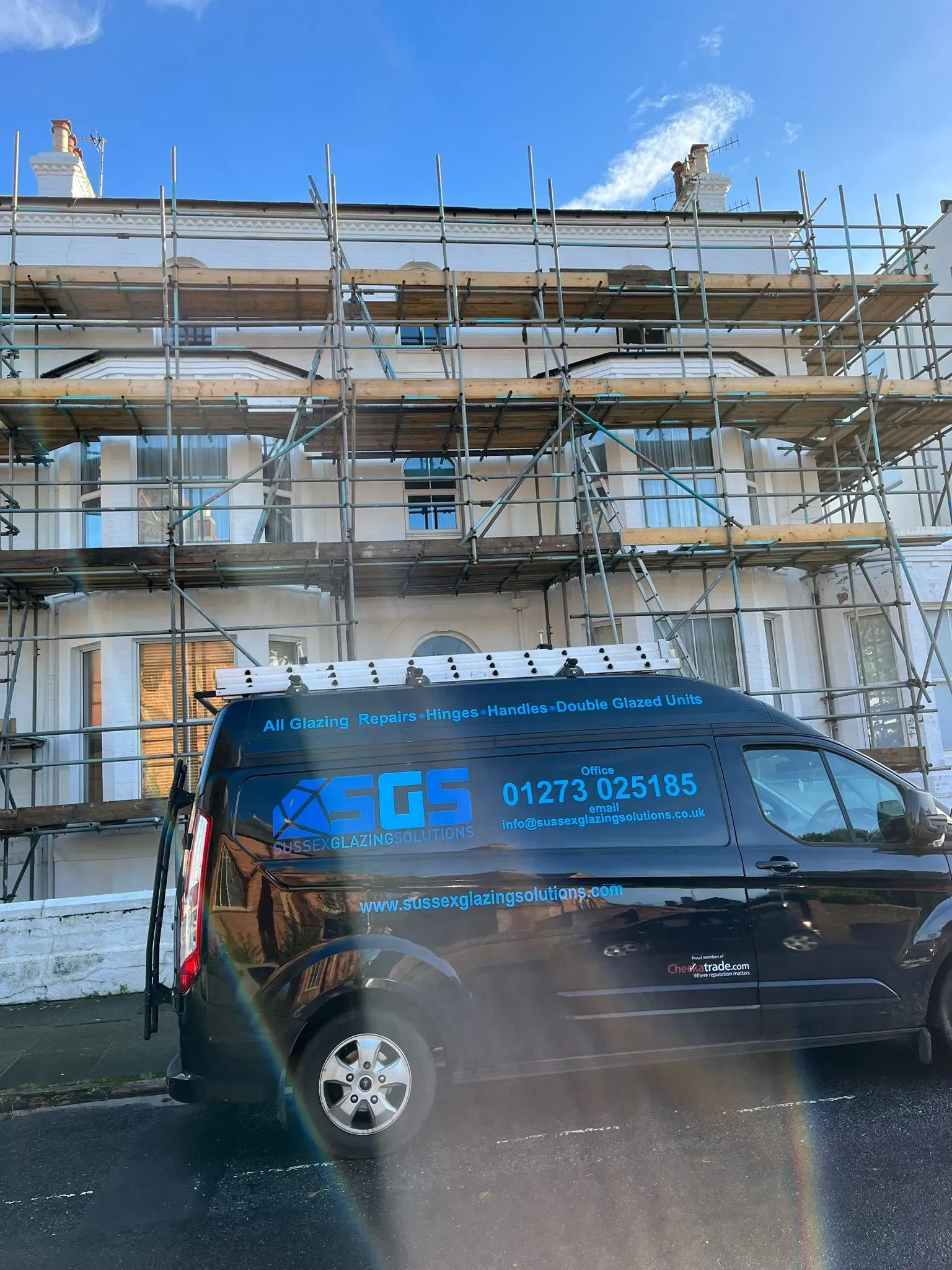 Van parked in front of a building under scaffolding for repairs